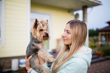 pretty woman with long blonde hair holding small dog yorkshire terrier outdoor