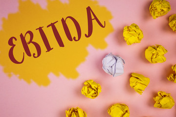 Word writing text Ebitda. Business concept for Earnings before tax is measured to evaluate company performance written Painted background Crumpled Paper Balls next to it.