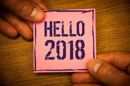 Conceptual hand writing showing Hello 2018. Business photo texts Starting a new year Motivational message 2017 is over nowMan hold holding pink note ideas black letters wooden background