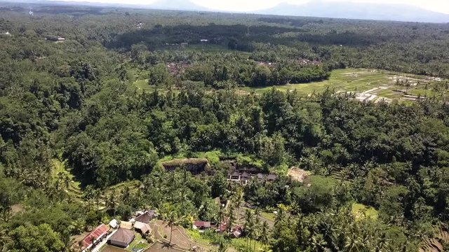 Above Ancient Temple Gunung Kawi, in Ubud, Bali in Indonesia. AERIAL BACKWARD SHOT. Temple in a Crater surrounding by forest. Revealing outside the temple.