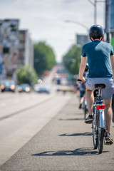 Fototapeta na wymiar Chain of cyclists rides on the sidewalk of a city street
