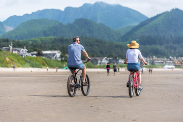 Mature couple rides bikes along the Pacific Ocean