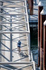 Man rides a bicycle on the transition between floating docks on the river