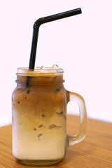 Layered Iced Coffee in glass mason jar on the table.