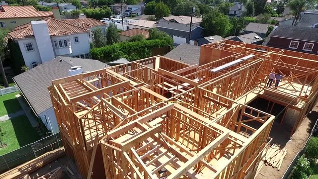 Aerial drone flying slowly over framed home during construction