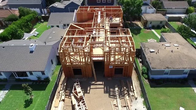 Aerial drone slowly descending over framed house during construction