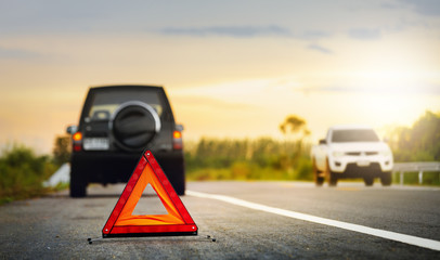 Red emergency stop sign (red triangle warning sign) and broken black SUV car  on country road.