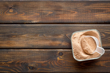 Sports nutrition with scoop and protein on wooden background top view space for text