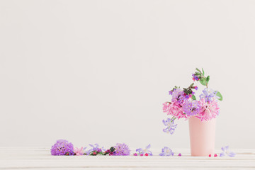 blue and pink flowers in vase on white table