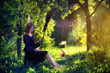 young witch by  fire in magic forest makes in cauldron magic potion