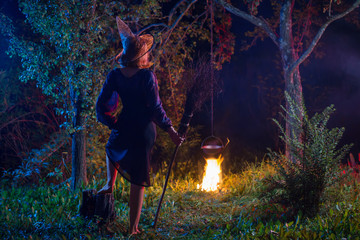young witch by  fire in night forest