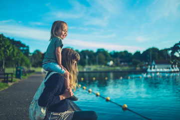 Little toddler on his mother's shoulders by a lake