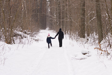 A little girl with her mother in the winter forest. The concept of family.