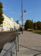 Naklejka premium Dawn in the residential part of the big city on the central streets.The bright dawn sun illuminates houses, sidewalks, a street in the city.