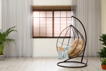 Comfortable swing chair with pillow in room interior