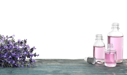 Obraz na płótnie Canvas Bottles of essential oil and lavender flowers on blue wooden table against white background