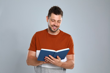 Handsome man reading book on light background