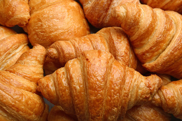 Fresh tasty croissants as background, closeup. French pastry