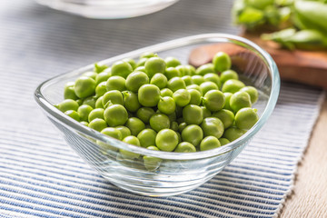 Fresh green pea seeds in bowl on kitchen table