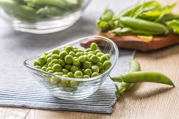 Fresh green pea seeds in bowl on kitchen table