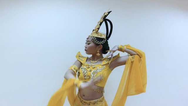 Beautiful asian woman dancing with hands with long nail manicure in a traditional thai yellow dress