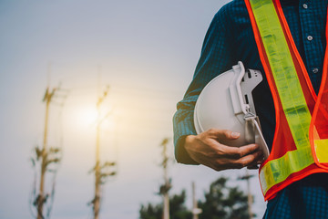 Engineering holds white safety hats and electric pole background