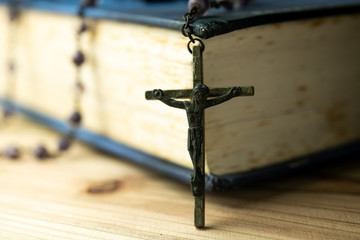 Closeup Catholic rosary beads with crucifix on wooden background.