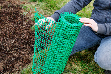 A woman holds a plastic net that is useful in gardening.