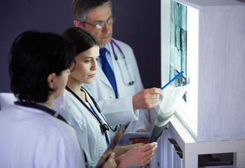 Group of doctors examining x-rays in a clinic, thinking of a diagnosis