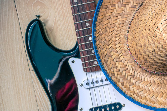 Electronic guitar and cowboy hat on wooden desk close up view. Country music concept.
