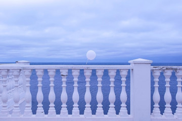 Promenade overlooking the sea on a gloomy rainy day. White balloon in the wind tied to the fence....