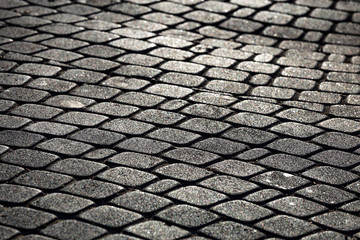 Cobble paving stone sidewalk of old town in evening sunlight. Abstract background.