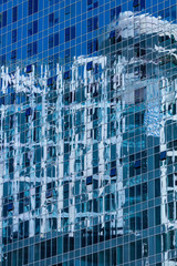 Closeup reflection of buliding in glass fasade of skyscraper. Business concept of architecture. Blue tone.