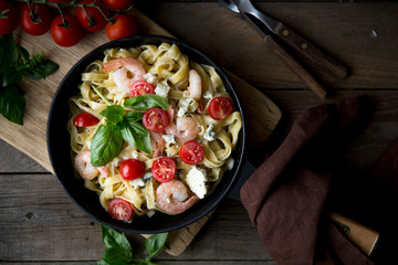 Tagliatelle pasta with shrimps and tomato sauce on dark background. Italian cuisine. Top view