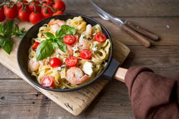 Tagliatelle pasta with shrimps and tomato sauce on dark background. Italian cuisine. Top view