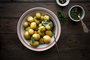 Potato. Tasty Young boiled potatoes with basil in white bowl on rustic wooden table.