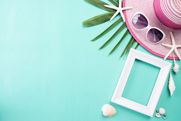 Beach accessories retro film camera, sunglasses, flip flop starfish beach hat and sea shell on green pastel background for summer holiday and vacation concept.