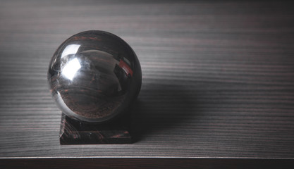 Black crystal ball on wooden desk.
