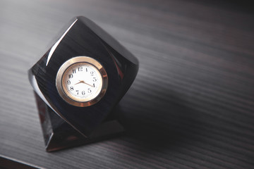Black clock on wooden desk.