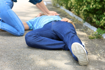 Woman giving CPR to unconscious man outdoors