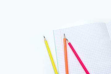 Blank notebook and pencils on white background. School supplies. White sketch book with colourful pencils. Note book and pencil