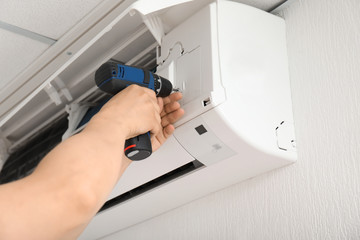 Electrician repairing air conditioner indoors