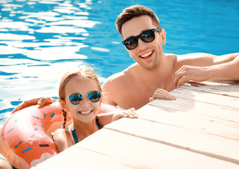 Father with little girl in swimming pool on summer day