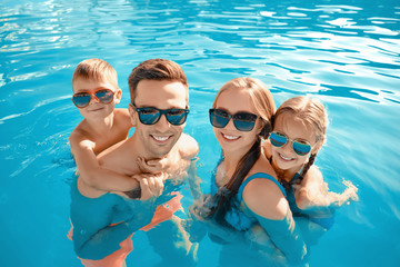 Happy family in swimming pool on summer day - Powered by Adobe