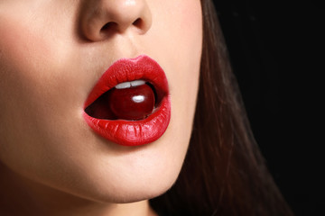 Beautiful young woman with cherry in mouth, closeup