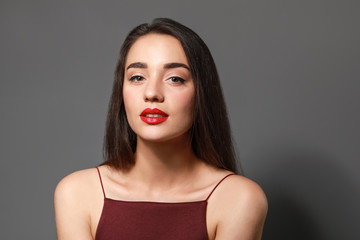 Beautiful young woman with bright lipstick on grey background