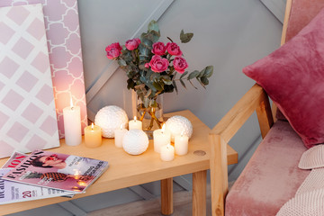 Beautiful burning candles and bouquet of flowers on table in room