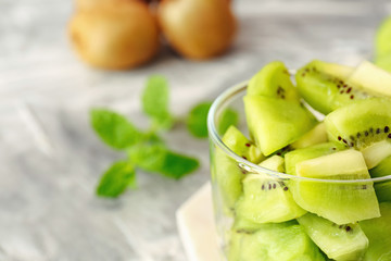 Container with tasty ripe kiwi on table, closeup