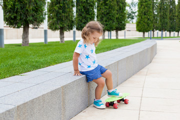 a charming girl with two tails learns to skate to skateboard on a Sunny summer day. Active healthy leisure and outdoor sport for kids. Fun activity for kid.