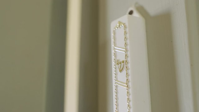 Fingers touch the Mezuzah and the Hebrew letter Shin on it